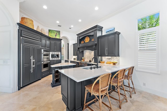 kitchen with sink, a kitchen bar, decorative backsplash, built in appliances, and kitchen peninsula