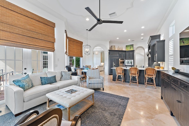 living room featuring ornamental molding and ceiling fan with notable chandelier