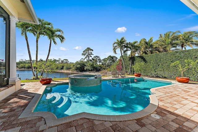 view of pool with an in ground hot tub, a water view, and a patio area