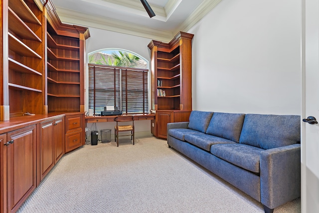 interior space featuring a raised ceiling, ornamental molding, and built in desk