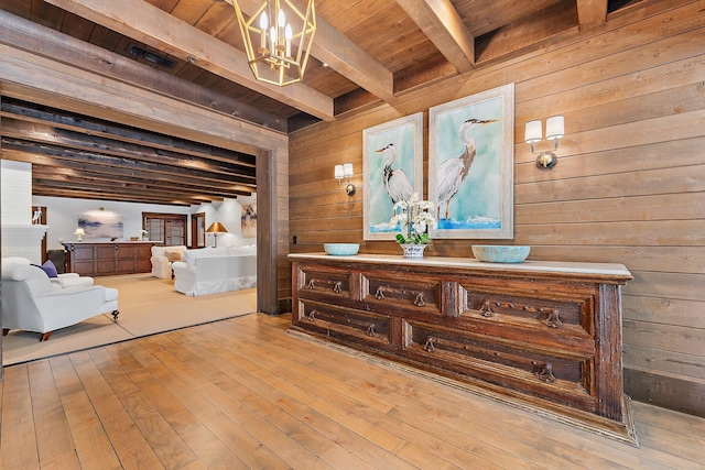 sitting room featuring beamed ceiling, wood ceiling, wooden walls, and light hardwood / wood-style flooring