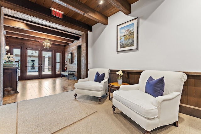 sitting room with wooden walls, wooden ceiling, french doors, and beamed ceiling