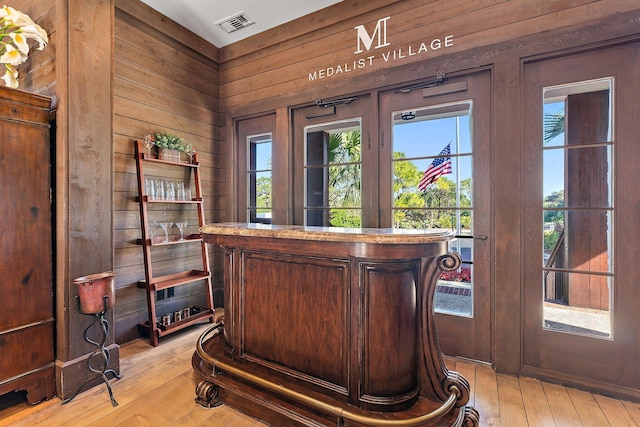 office area with light hardwood / wood-style flooring and wood walls