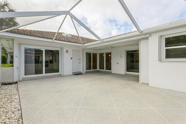 exterior space with stucco siding, a tile roof, a ceiling fan, and a patio