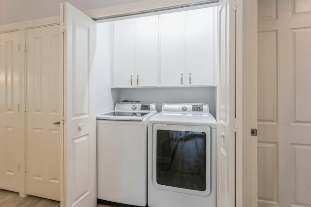 laundry area with cabinet space, light wood finished floors, and washer and dryer