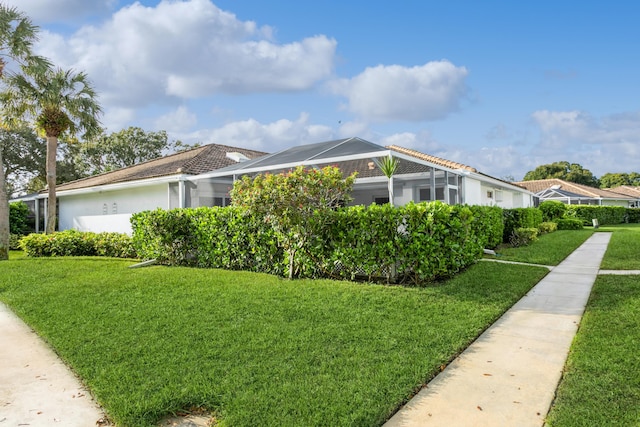 view of property exterior with a lawn, a tile roof, and a lanai