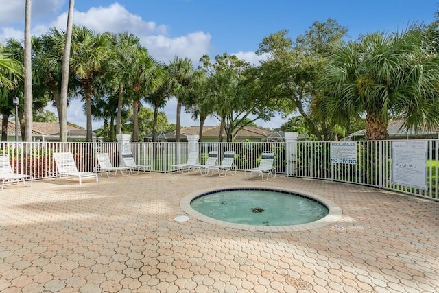 view of swimming pool featuring a community hot tub, a patio area, and fence