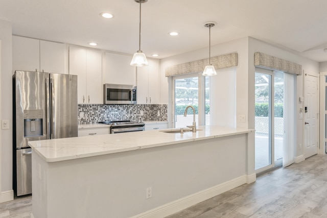 kitchen featuring stainless steel appliances, a sink, white cabinets, a wealth of natural light, and tasteful backsplash