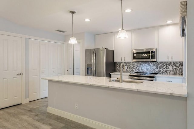 kitchen with white cabinets, appliances with stainless steel finishes, pendant lighting, and sink