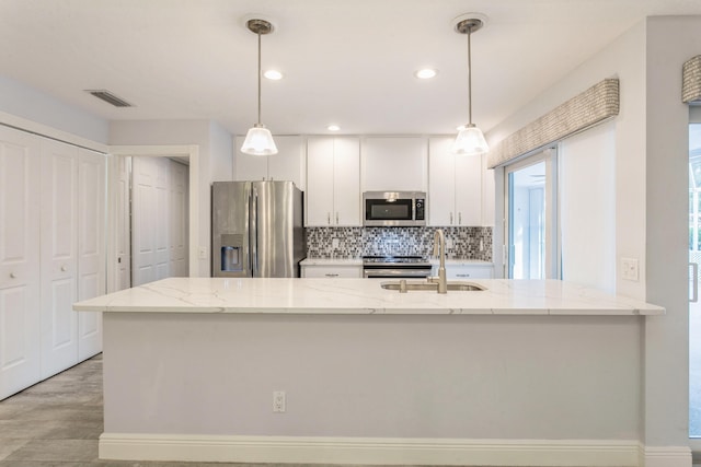 kitchen with decorative backsplash, light stone counters, appliances with stainless steel finishes, white cabinetry, and a sink