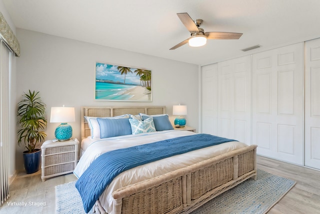 bedroom featuring light wood-style floors, a closet, visible vents, and a ceiling fan