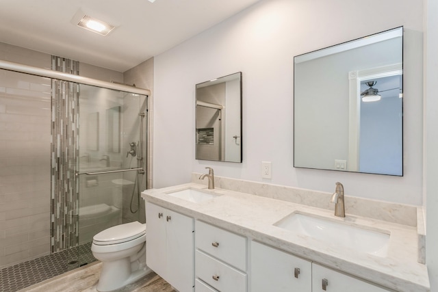 full bath featuring toilet, a shower stall, double vanity, and a sink