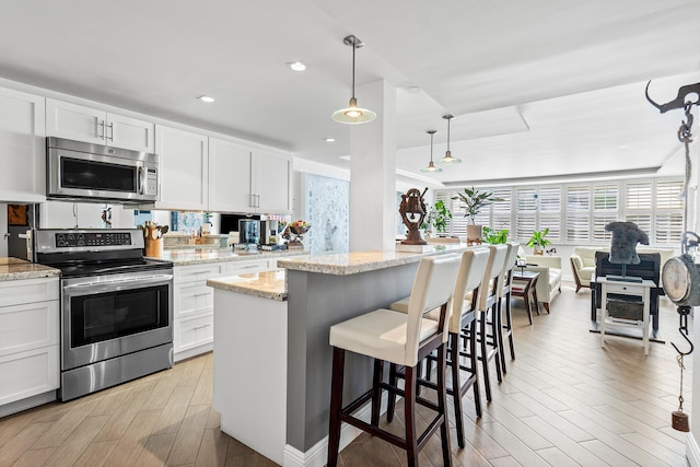 kitchen featuring white cabinets, appliances with stainless steel finishes, and pendant lighting