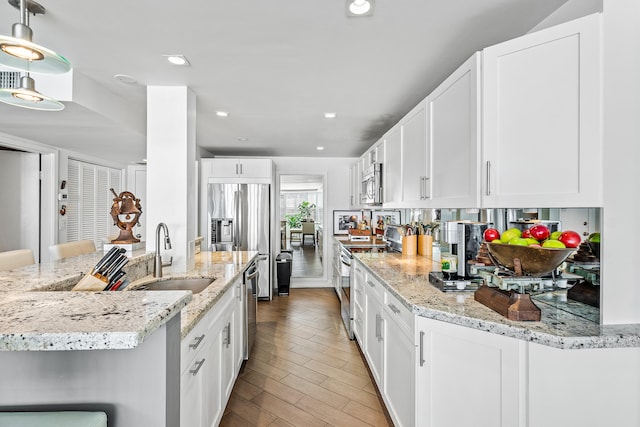 kitchen featuring white cabinets, a kitchen breakfast bar, hanging light fixtures, and sink