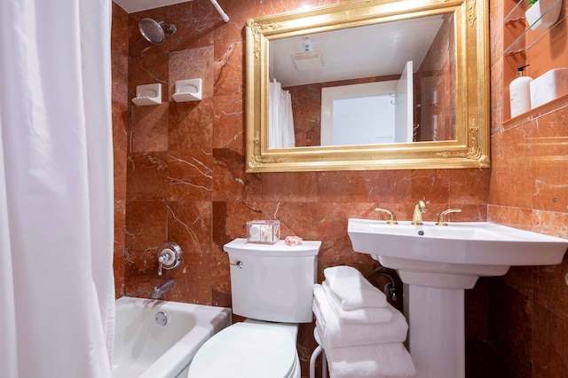 full bathroom featuring sink, shower / bath combo with shower curtain, toilet, and tile walls