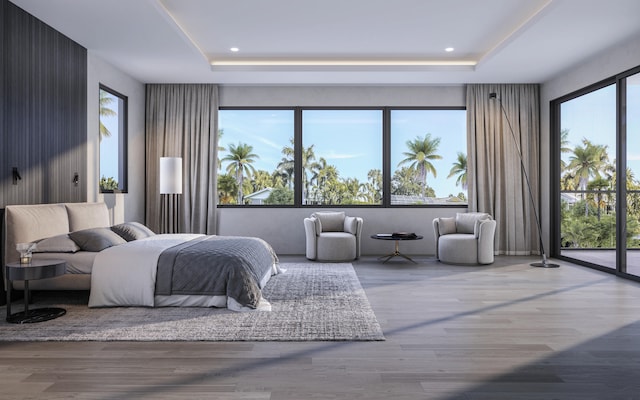 bedroom featuring a raised ceiling, multiple windows, and hardwood / wood-style flooring