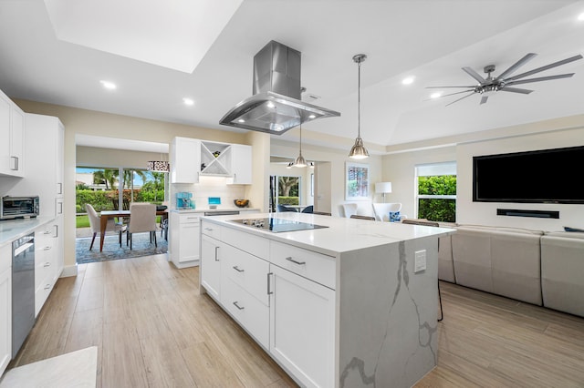 kitchen featuring a wealth of natural light, island range hood, white cabinets, and light stone counters