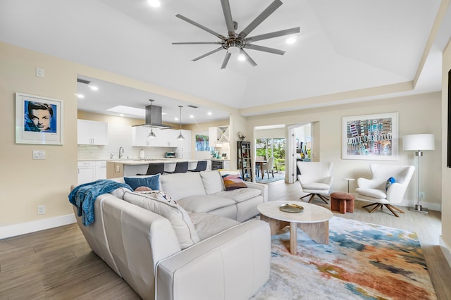 living room featuring sink, vaulted ceiling, light hardwood / wood-style floors, and ceiling fan