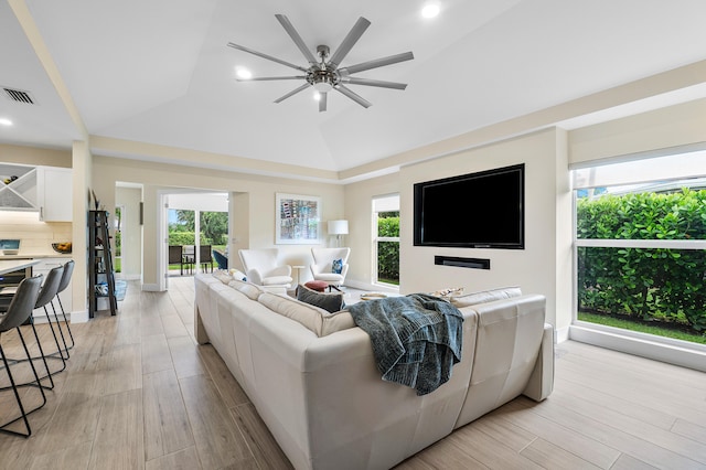 living room featuring light hardwood / wood-style flooring, lofted ceiling, ceiling fan, and a wealth of natural light