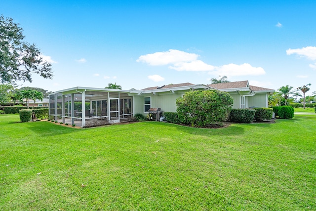 rear view of house with a yard and a sunroom