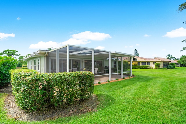 rear view of property with a yard, a patio, and glass enclosure