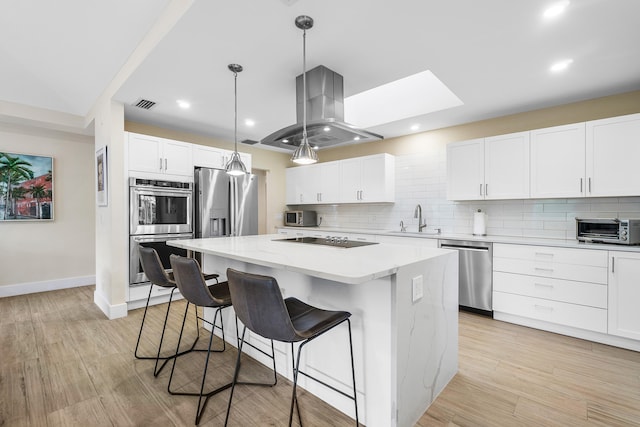 kitchen with a kitchen island, white cabinetry, island range hood, sink, and stainless steel appliances