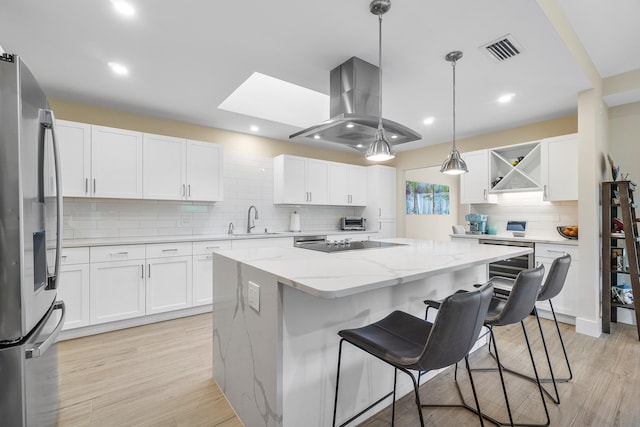 kitchen with island range hood, a center island, light wood-type flooring, white cabinets, and stainless steel refrigerator