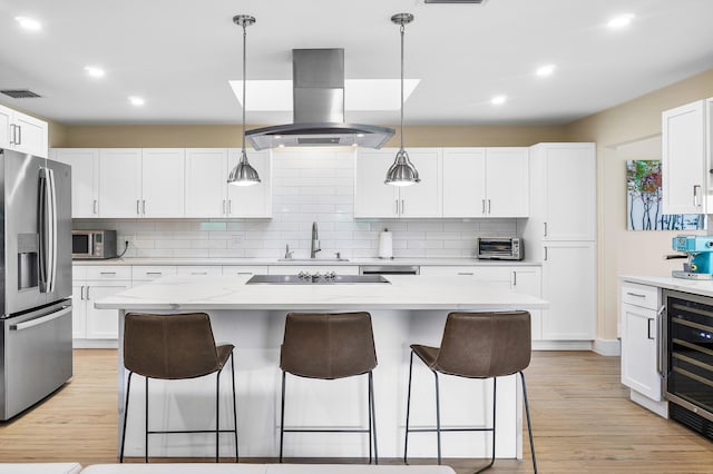 kitchen featuring island range hood, a center island, white cabinetry, stainless steel appliances, and pendant lighting