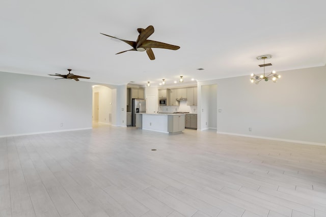 unfurnished living room featuring ceiling fan with notable chandelier