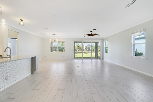 unfurnished living room with ceiling fan with notable chandelier, ornamental molding, and sink