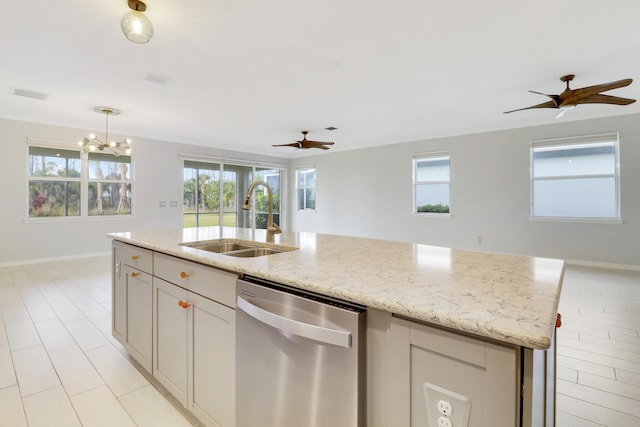 kitchen featuring light stone countertops, sink, stainless steel dishwasher, an island with sink, and pendant lighting