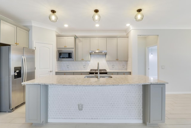 kitchen with stainless steel appliances, light stone counters, a kitchen island with sink, and sink