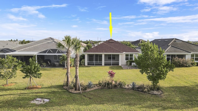 back of property featuring a lawn, glass enclosure, and a sunroom