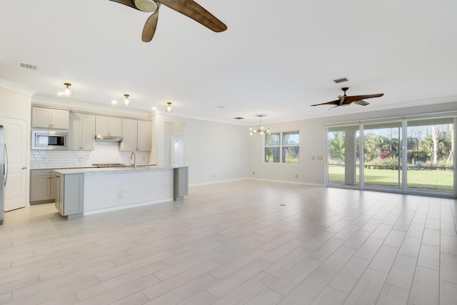 unfurnished living room featuring ceiling fan with notable chandelier and ornamental molding