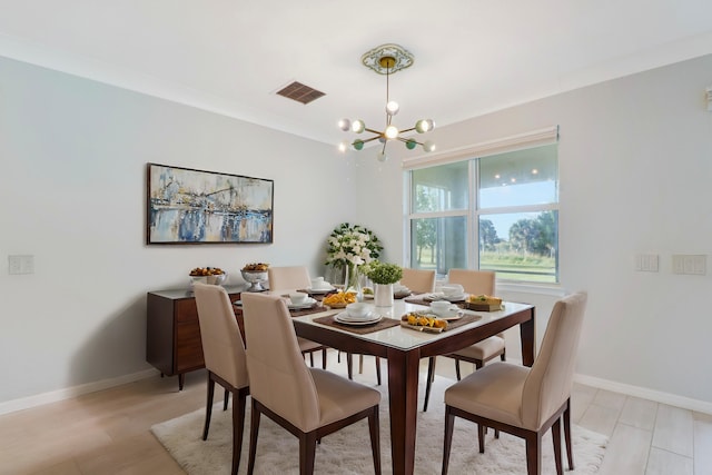 dining room featuring crown molding, light hardwood / wood-style flooring, and a chandelier