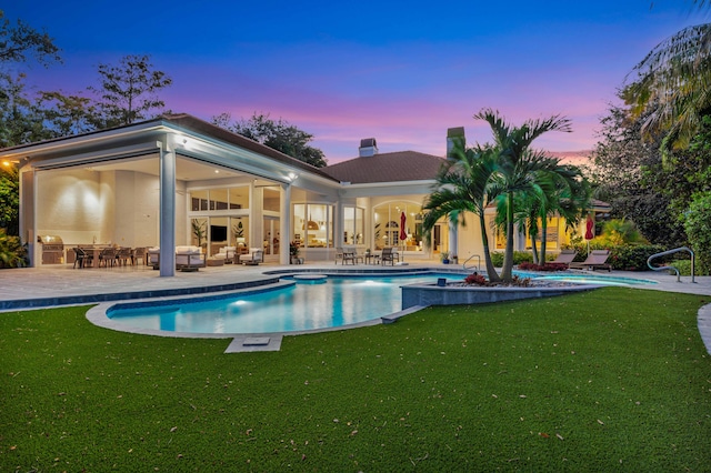 pool at dusk featuring a patio and a yard