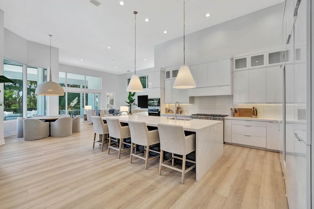 kitchen with white cabinetry, a kitchen island with sink, and light hardwood / wood-style floors