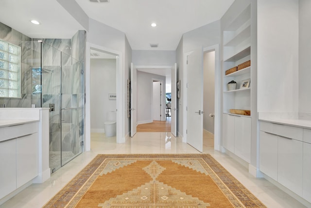 bathroom with a shower with shower door, toilet, vanity, tile patterned flooring, and built in shelves