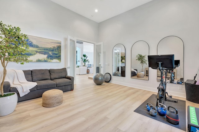 workout room with a towering ceiling and light wood-type flooring