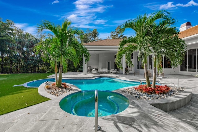 view of pool with an in ground hot tub, a patio area, and a lawn