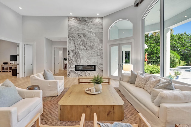 living room with a high ceiling, light wood-type flooring, and a high end fireplace