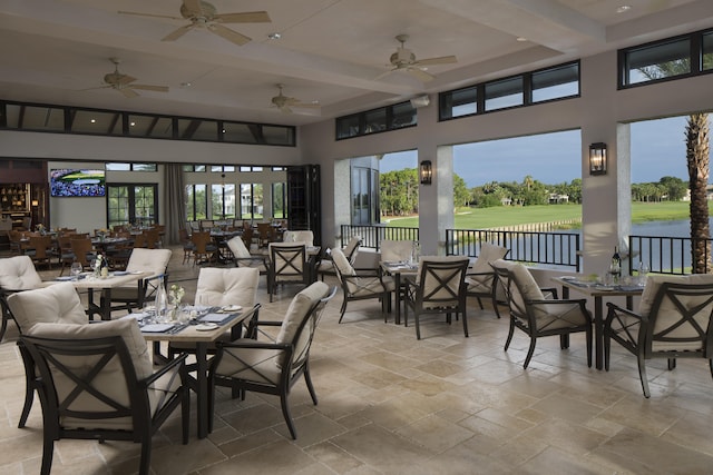 sunroom / solarium featuring beamed ceiling, a water view, a healthy amount of sunlight, and ceiling fan