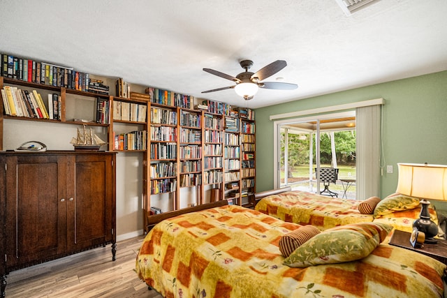 bedroom featuring light hardwood / wood-style floors, access to exterior, a textured ceiling, and ceiling fan