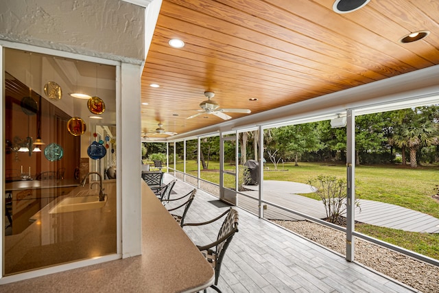 unfurnished sunroom with sink, wood ceiling, and ceiling fan