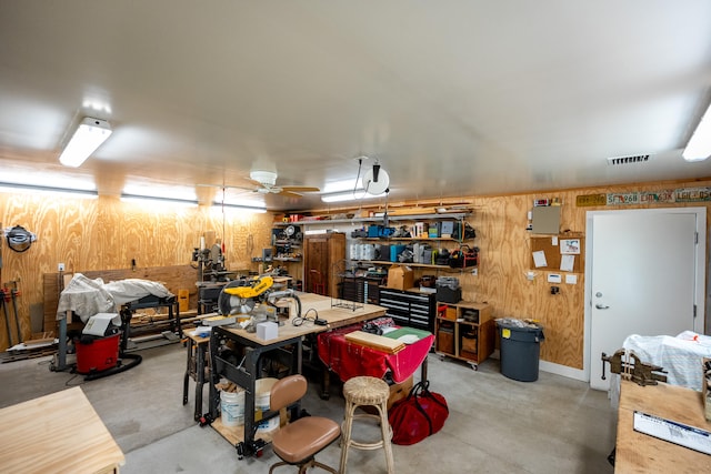 garage featuring wood walls, a workshop area, and ceiling fan