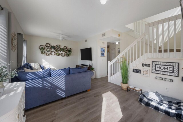 living room featuring dark wood-type flooring and ceiling fan