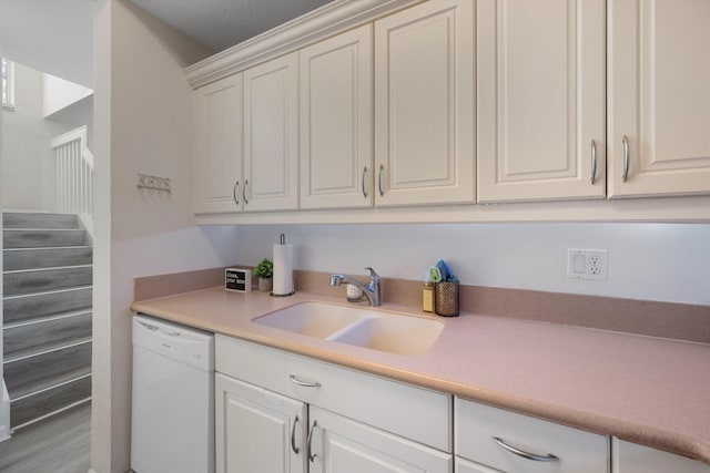 kitchen with light hardwood / wood-style flooring, white cabinetry, sink, and white dishwasher