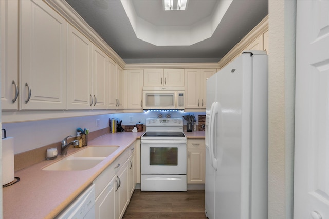 kitchen featuring cream cabinetry, sink, a raised ceiling, white appliances, and dark hardwood / wood-style flooring