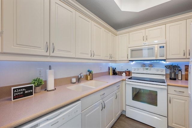 kitchen featuring white appliances, wood-type flooring, and sink