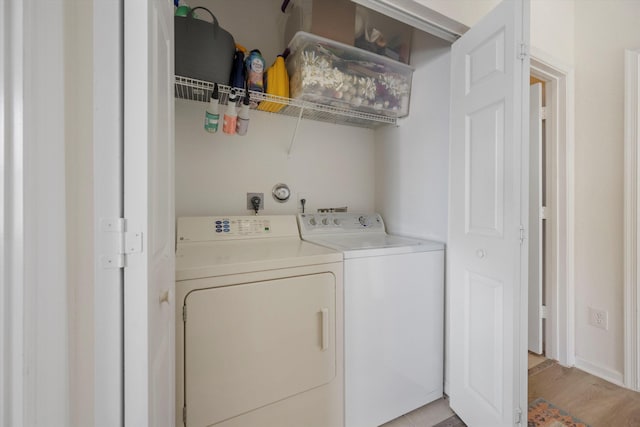 laundry area with independent washer and dryer and light hardwood / wood-style flooring